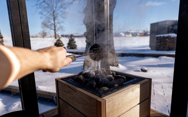 Auf dem Bild ist zu sehen, wie eine Hand ein Aufguss in der Sauna macht.